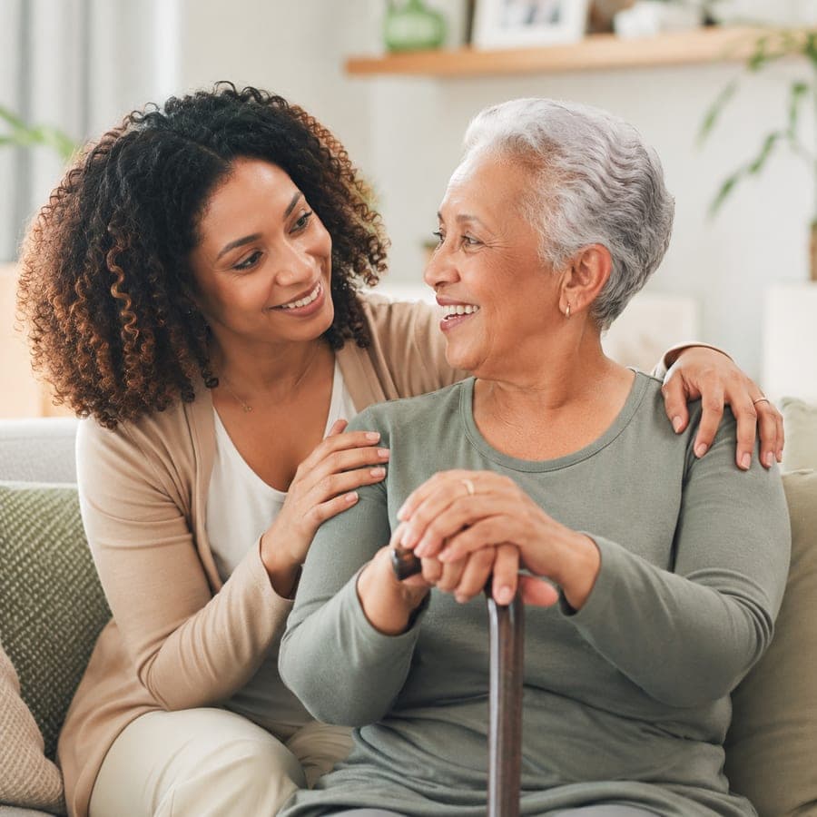 An adult daughter with her arm around her mother, sharing a warm moment together